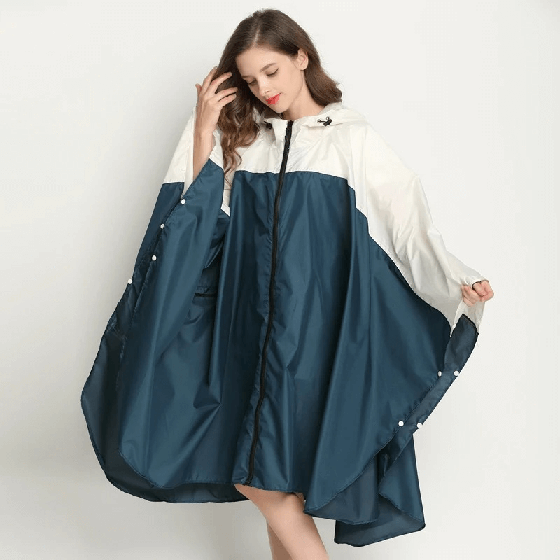 Woman wearing a stylish blue and white raincoat poncho with hood, showcasing waterproof and windproof design, perfect for rainy days.