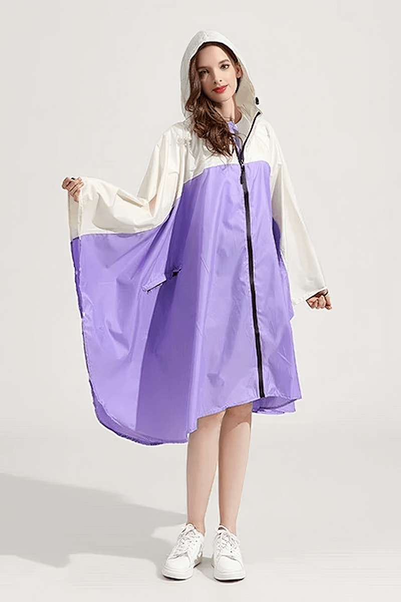 Woman wearing purple and white raincoat-poncho with hood and zipper, made of waterproof polyester, perfect for rainy days.