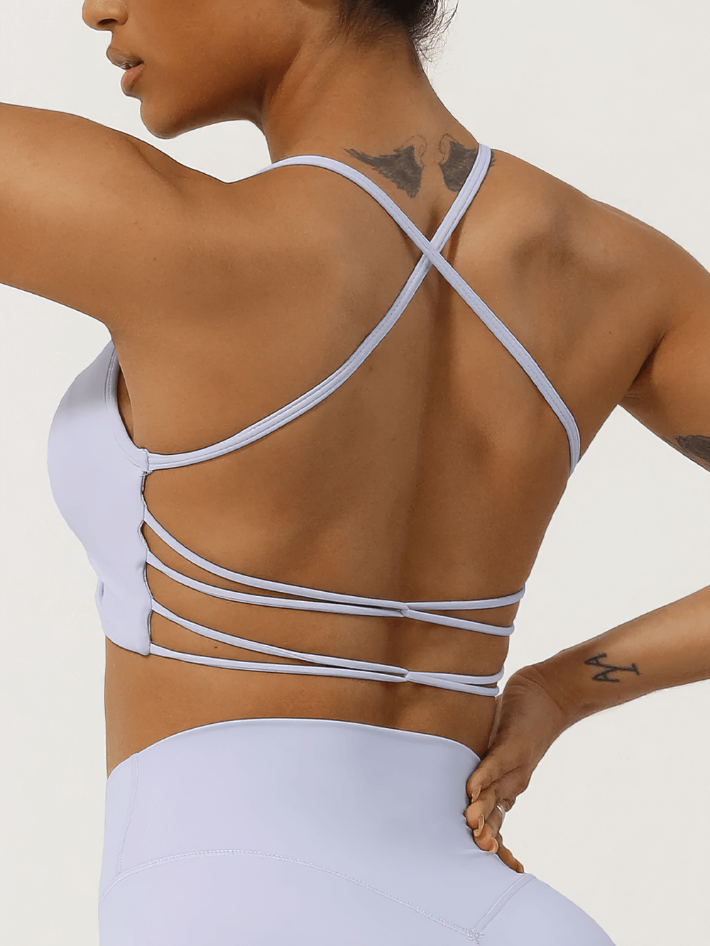 Rear view of a woman's ruched sports top with strappy back design, perfect for active wear and fitness enthusiasts.