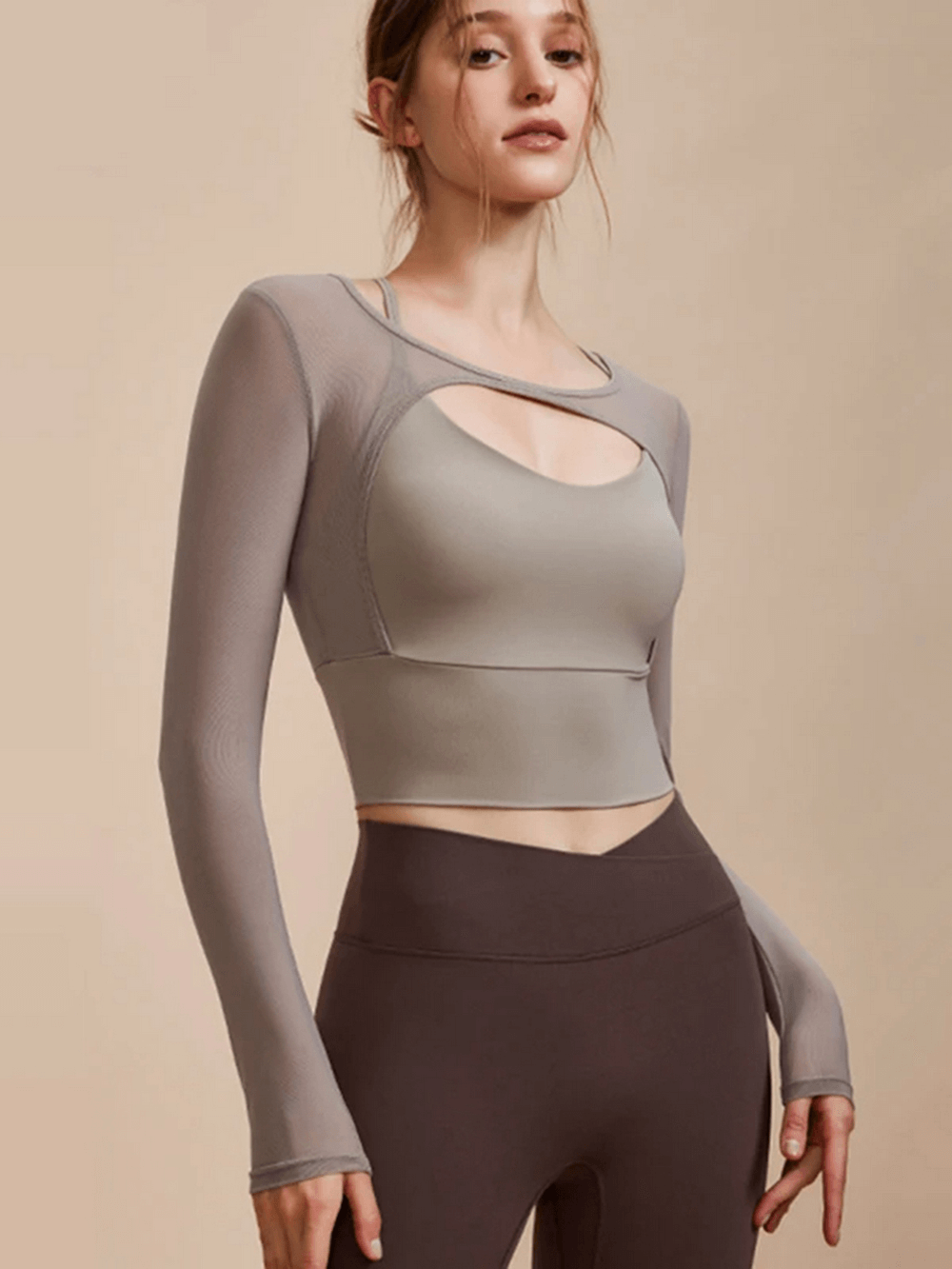 Woman wearing a seamless long sleeve yoga crop top in grey, designed for breathability and quick-drying during workouts.