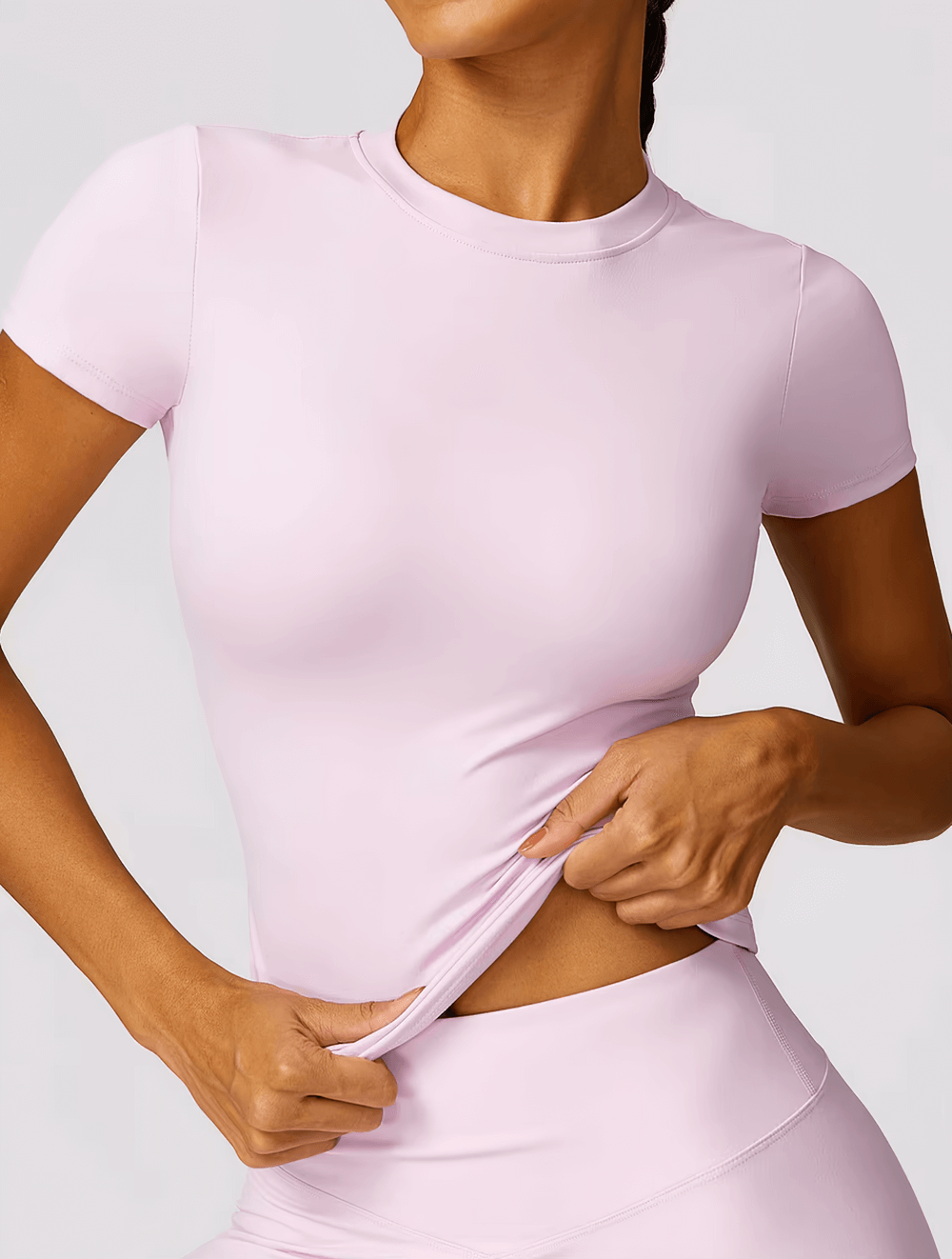 Woman wearing Women's Seamless Short-Sleeve Yoga T-Shirt in pink, showcasing its breathable nylon-spandex blend and slim fit design.