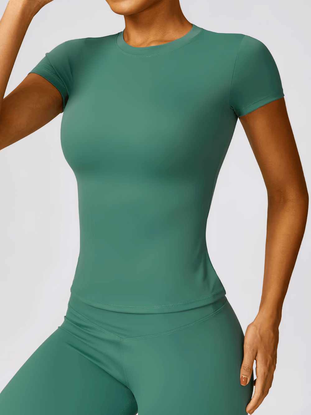 Woman wearing green seamless short-sleeve yoga T-shirt, perfect for gym and fitness activities, showcasing breathable and quick-dry fabric.