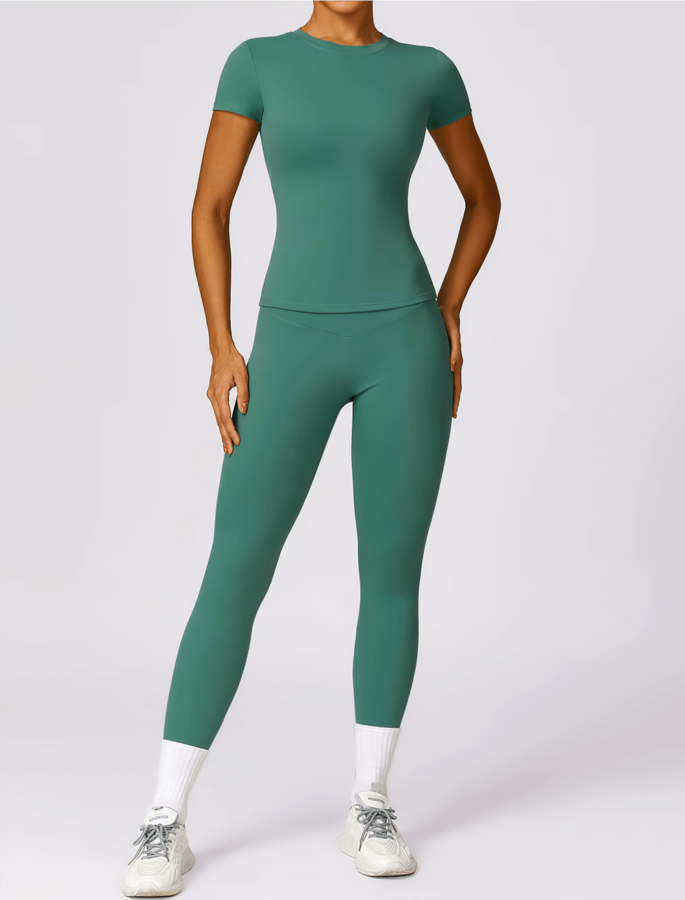 Woman wearing green seamless short-sleeve yoga t-shirt and leggings, perfect for fitness, made from breathable nylon and spandex.