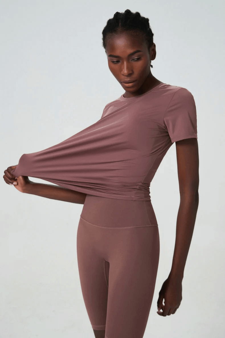 Woman wearing solid color two-piece yoga set made from breathable Lycra, showcasing anti-shrink and quick-dry features.