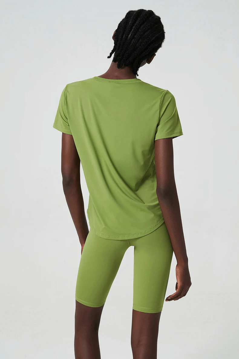 Back view of woman wearing green solid color two-piece yoga set, made from breathable Lycra for workouts, featuring short sleeves and quick-dry fabric.