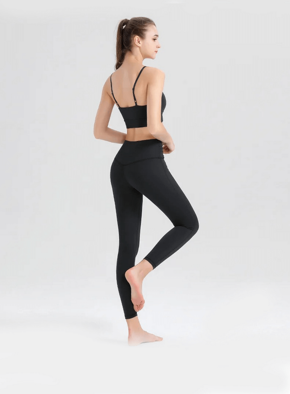 Woman wearing a black spandex workout set, featuring a sleeveless top and leggings, perfect for yoga and intense workouts.