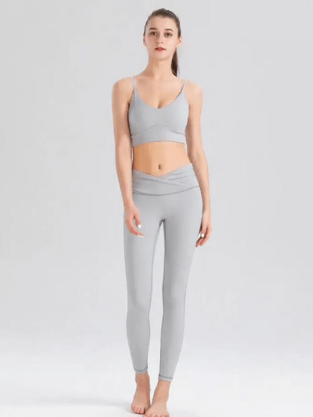 Woman wearing a gray spandex workout set with sleeveless top and leggings, showcasing the breathable and durable fitness outfit.