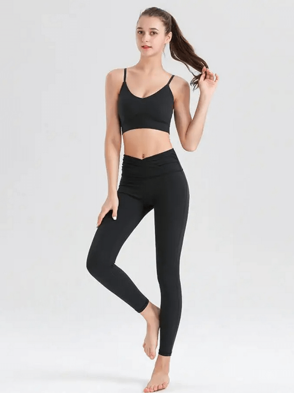 Woman wearing black spandex workout two-piece set, featuring a sleeveless top and matching leggings, ideal for yoga and fitness.