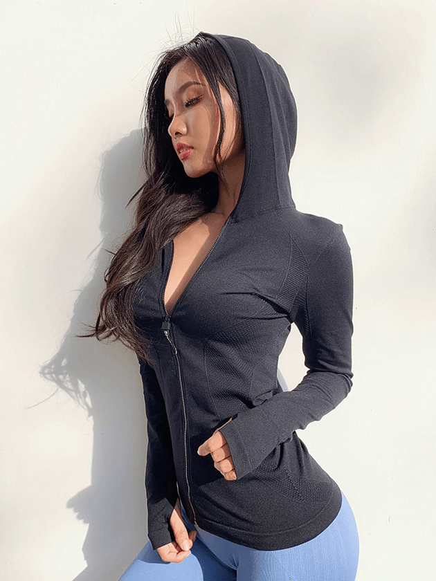 Woman wearing a black women's sports zipper hoodie with thumb hole, ideal for yoga and fitness, showcasing a stylish and breathable design.