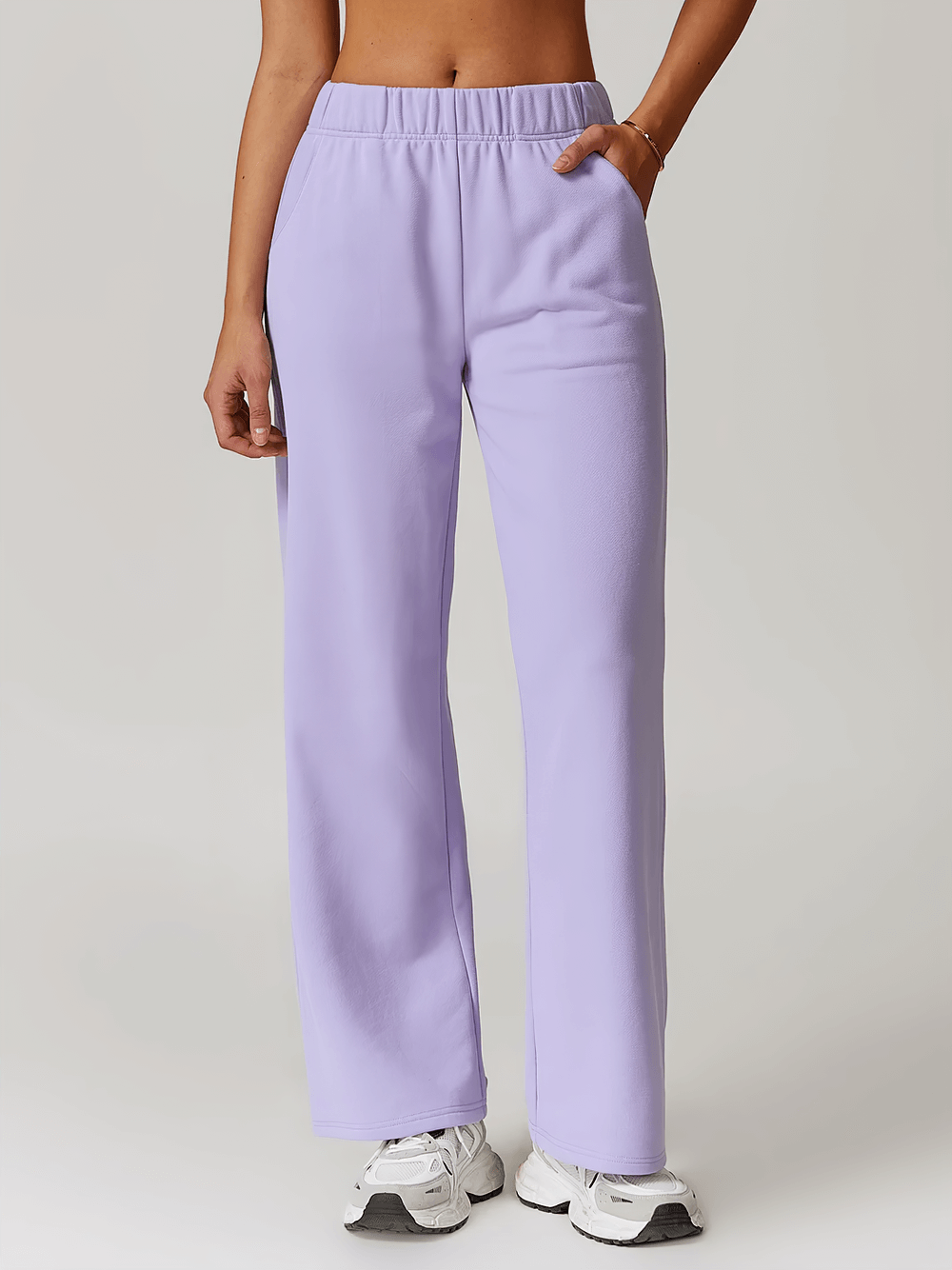 Model wearing lavender high-waist straight-leg sweatpants with sporty white sneakers, showcasing casual winter style.