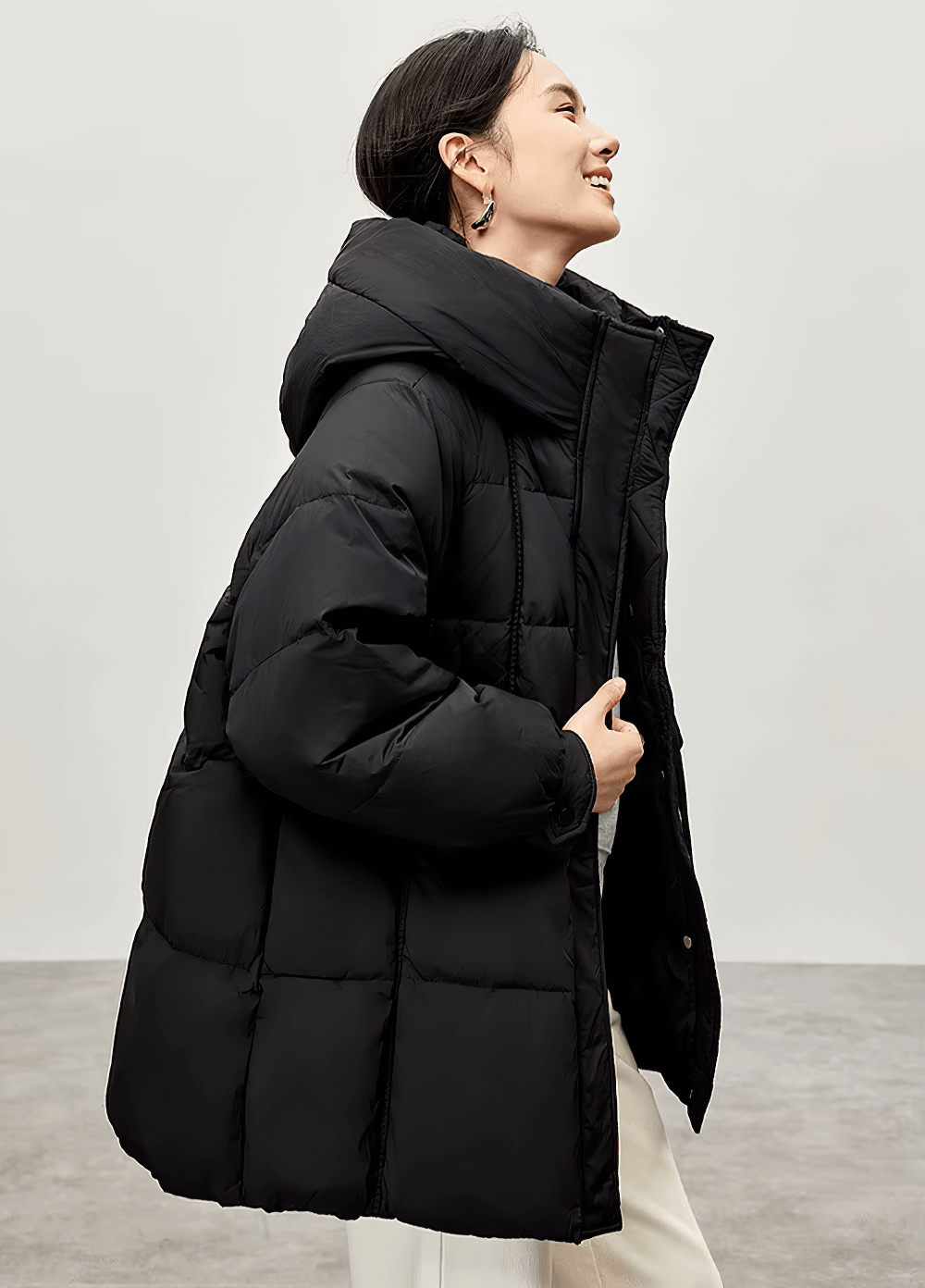 Woman wearing black hooded puffer jacket with stand neck, made from white duck down, perfect for winter days.