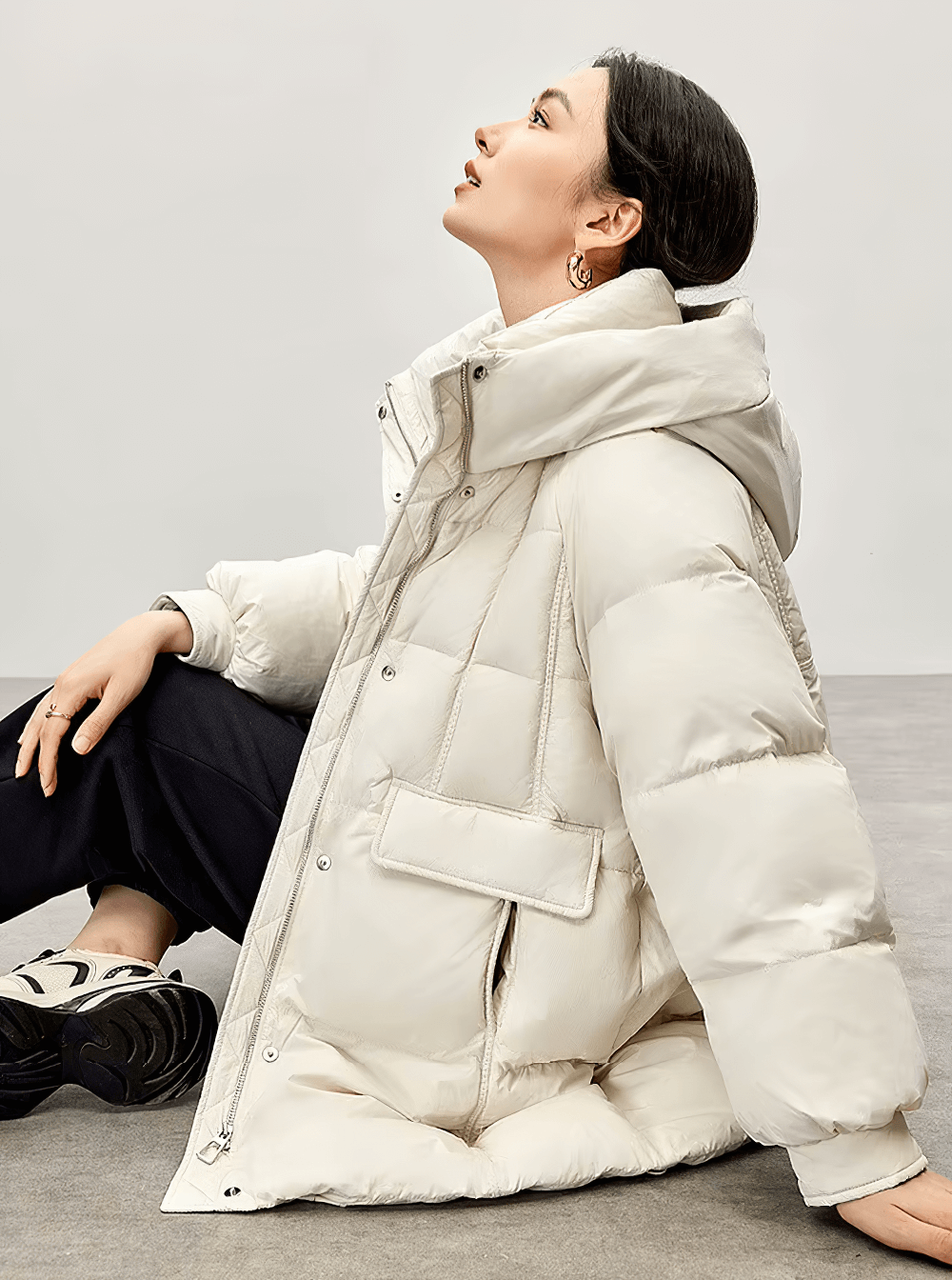 Woman wearing a white duck down hooded puffer jacket SF2309, featuring a stand neck and zipper closure, perfect for winter warmth.