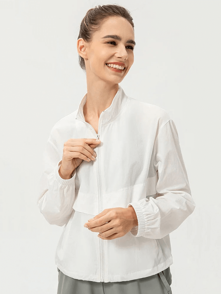 Woman wearing a white UV protection running windbreaker, showcasing lightweight and breathable fabric with a turn-down collar for outdoor sports.