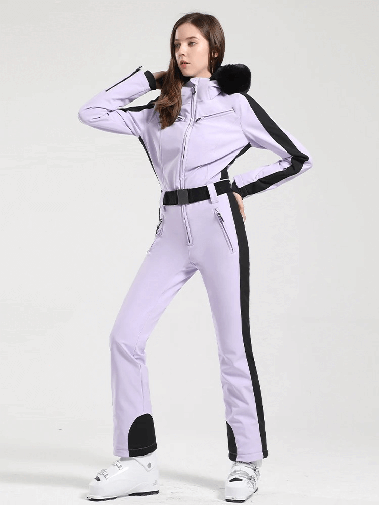 Woman in a stylish purple one-piece ski suit with black accents, featuring a hood, designed for warmth and performance on the slopes.