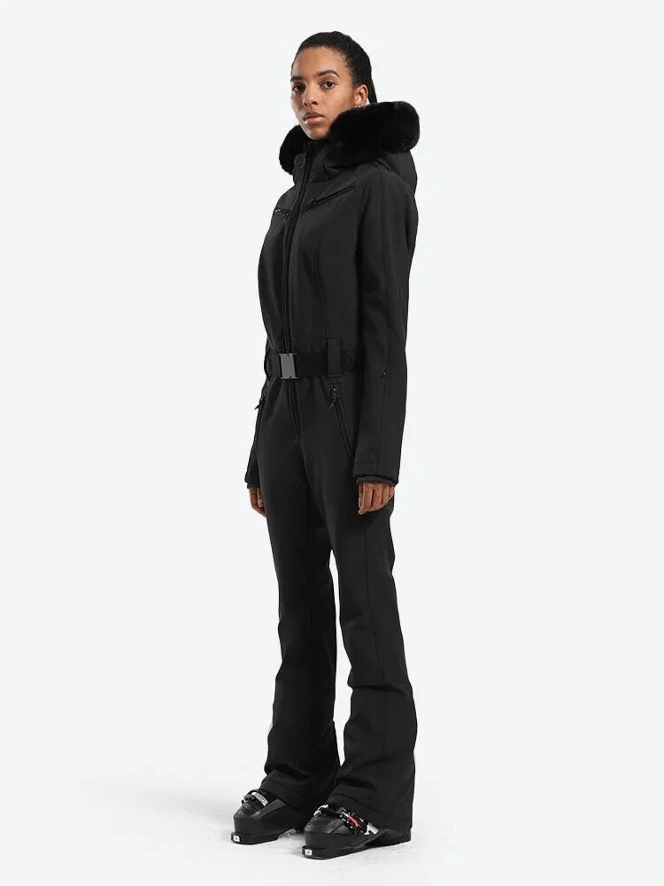 Women's warm one-piece ski suit with hood in black, designed for peak performance and protection, shown on a standing model.