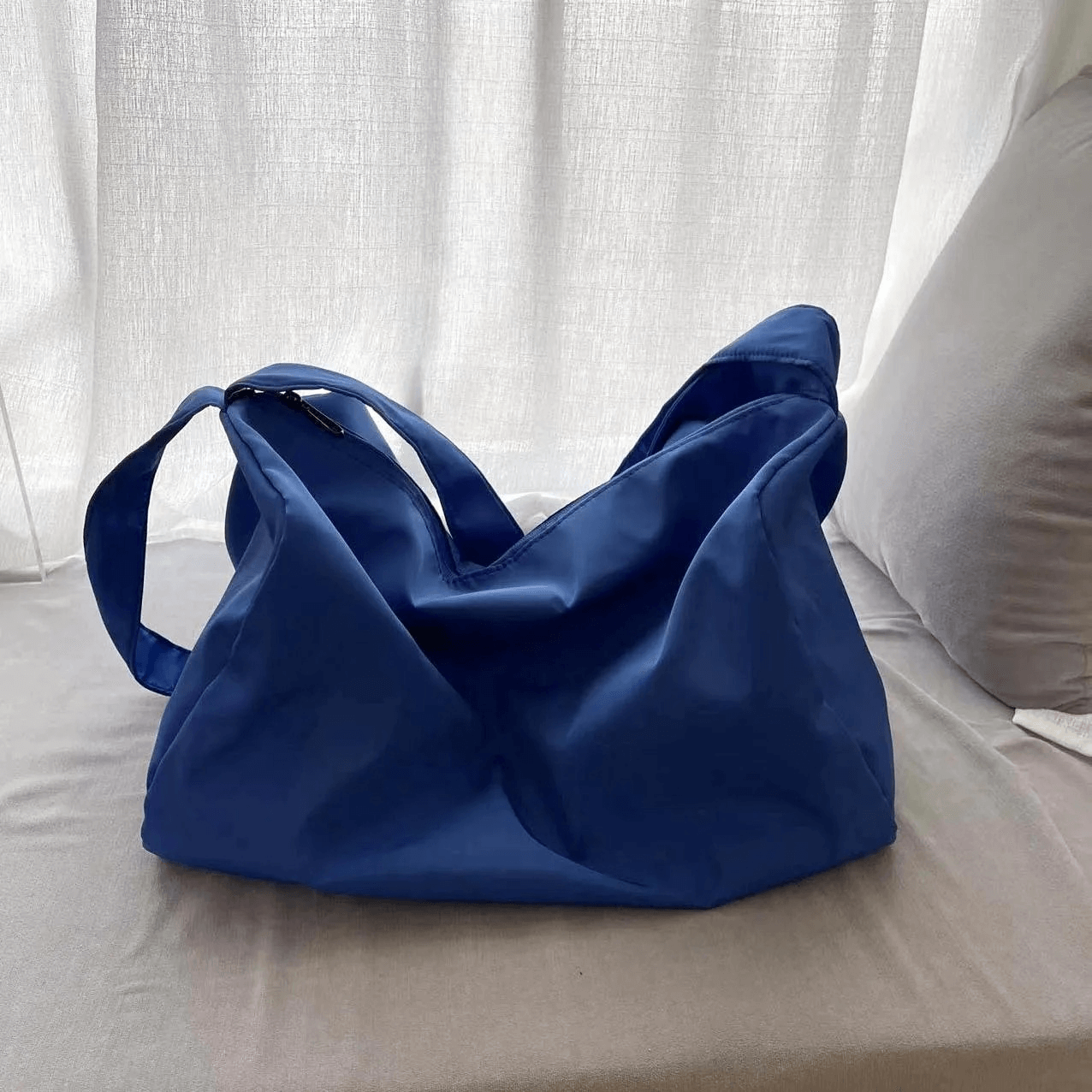 Blue women's waterproof large-capacity fitness tote bag on a grey sofa.