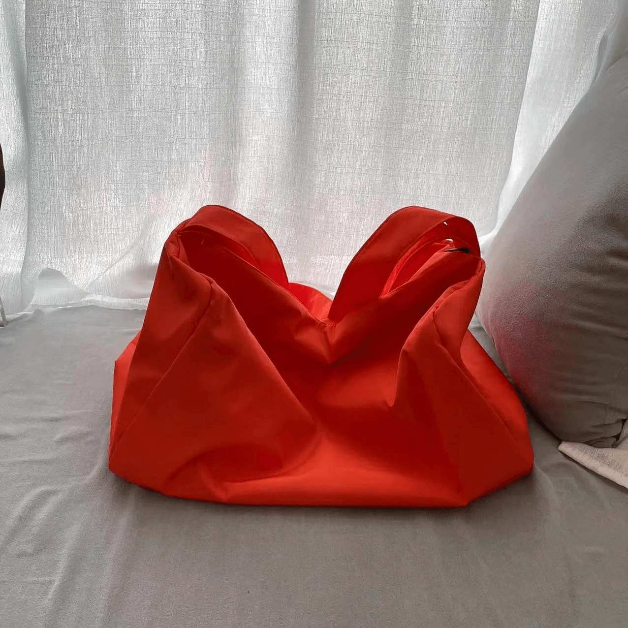 Bright red women's waterproof large-capacity fitness tote bag with zipper closure on a soft grey surface, perfect for workouts.