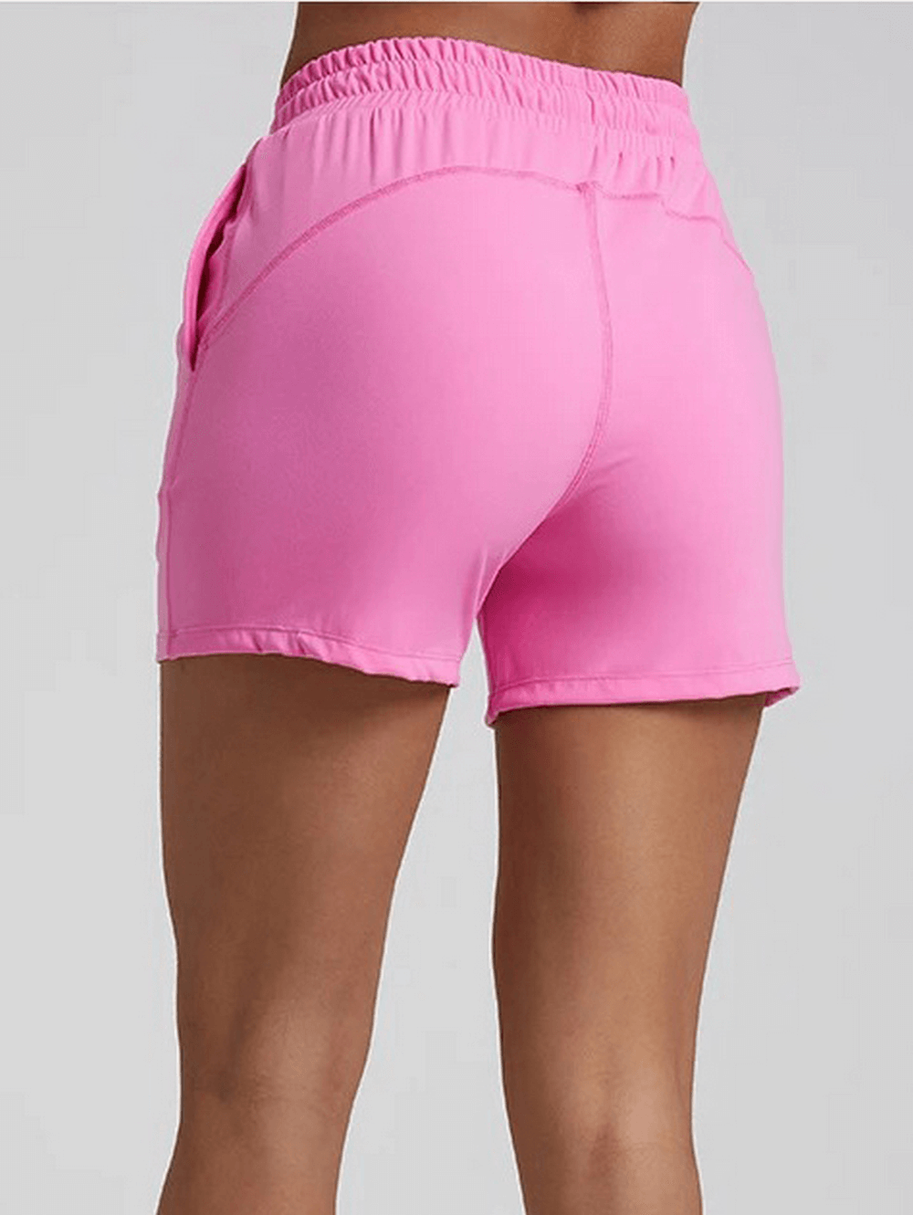 Back view of pink women's workout shorts with elastic waistband, made from flexible nylon and spandex. Perfect for athletic activities.