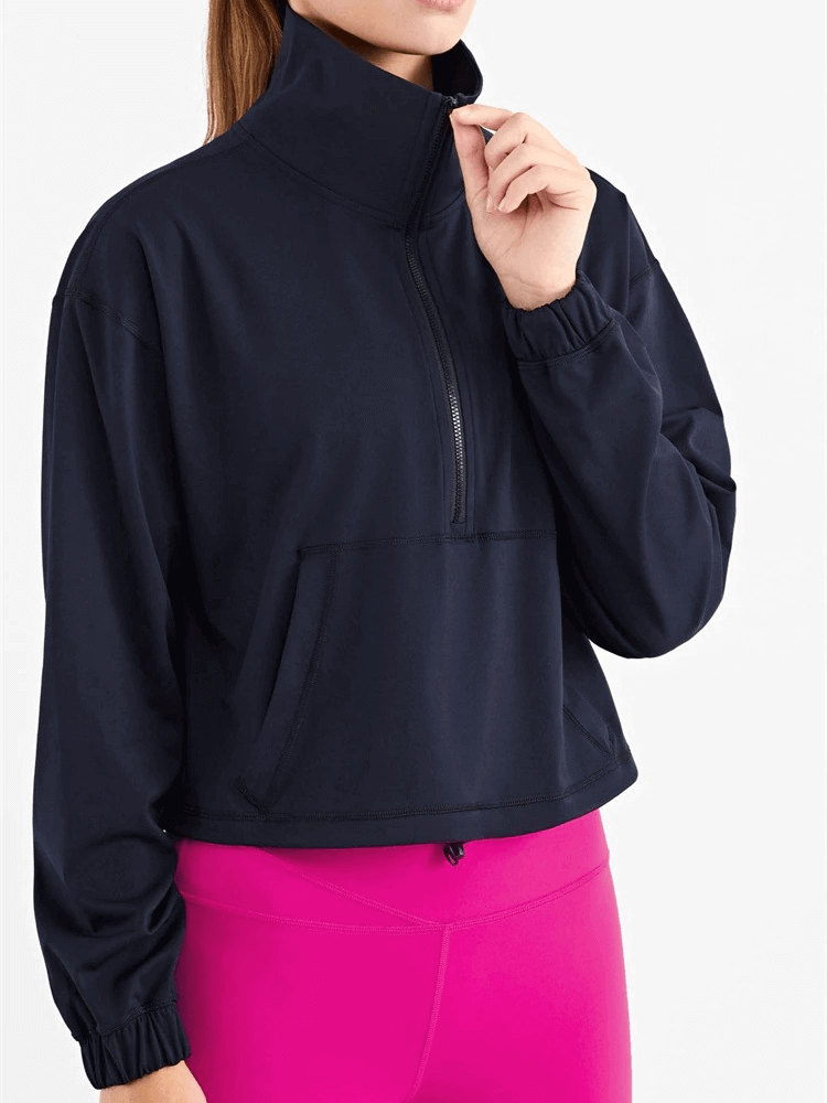 Woman wearing a black sports sweatshirt with v-neck and pocket, paired with bright pink leggings, showcasing a stylish fitness look.