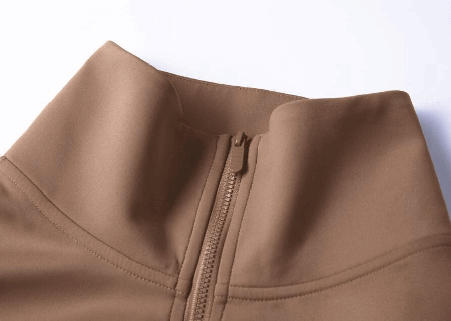 Close-up of a brown high-neck workout sweatshirt with a front zipper, highlighting the soft, durable fabric for fitness and comfort.
