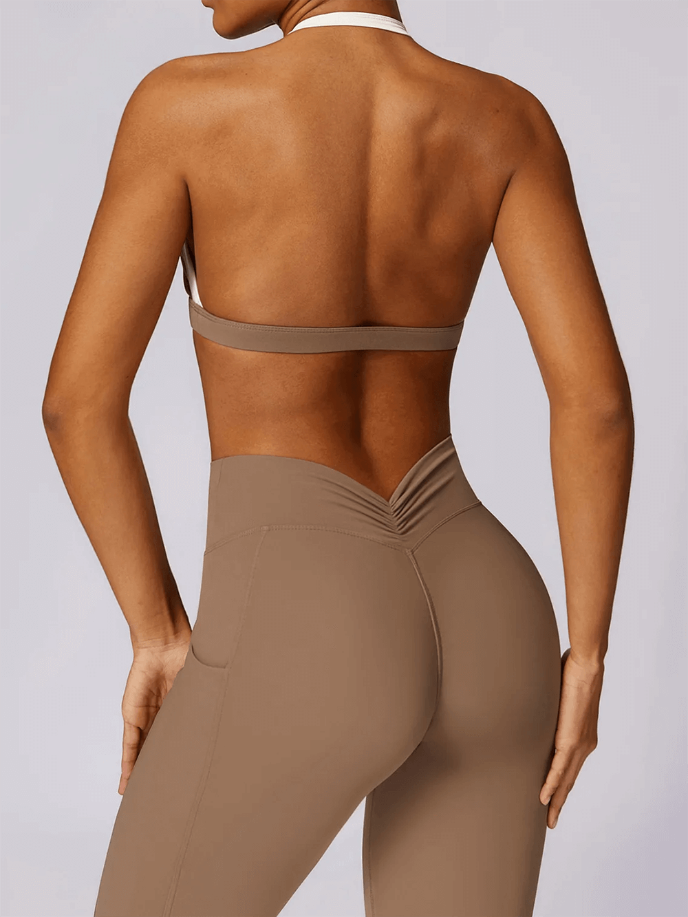Back view of woman wearing beige yoga set with sleeveless top and high-waist leggings, perfect for fitness and athletic activities.