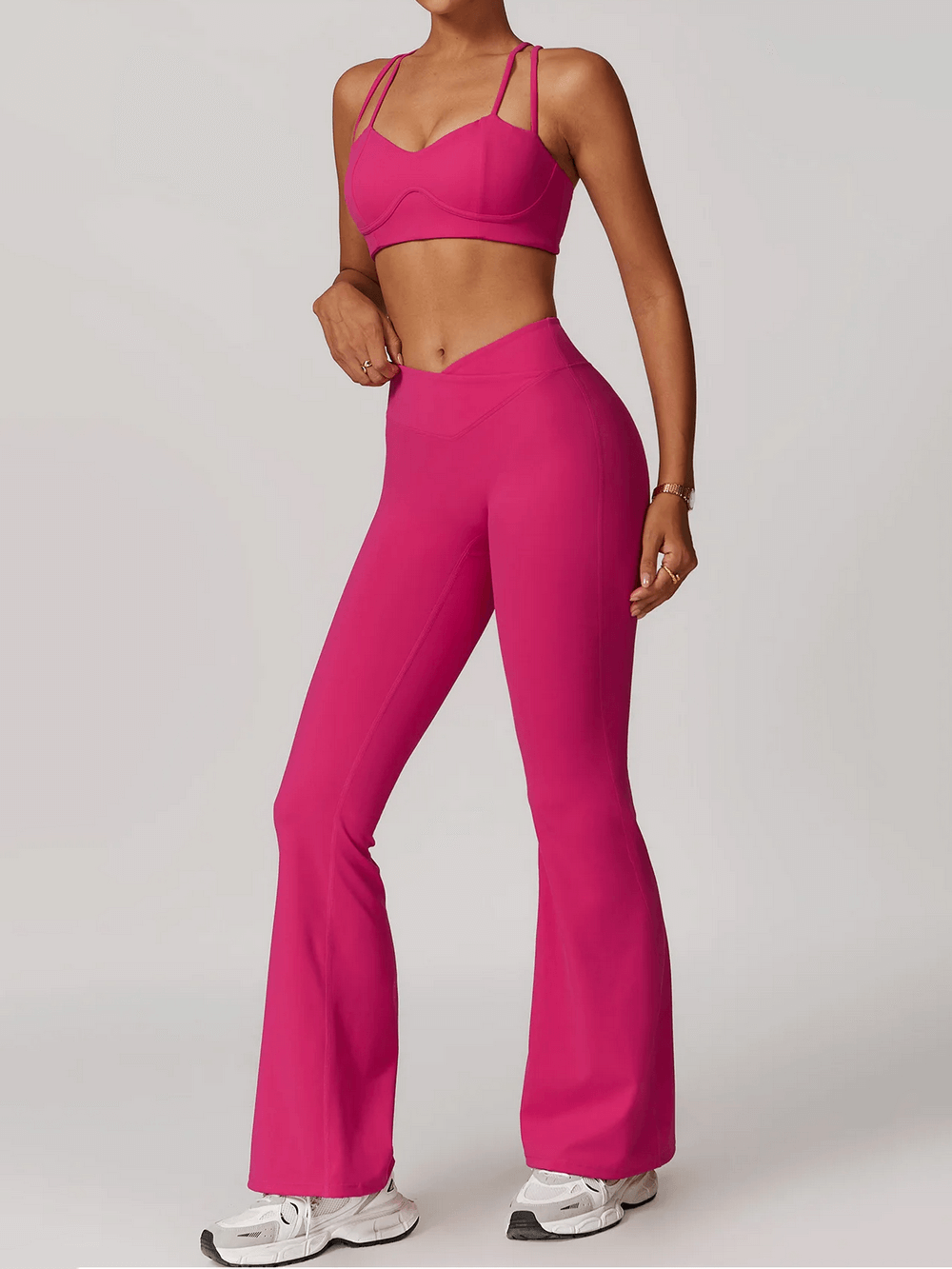 Woman in pink sleeveless yoga sports set with strappy bra and flared pants, ideal for fitness and running, showcasing durable fabric.