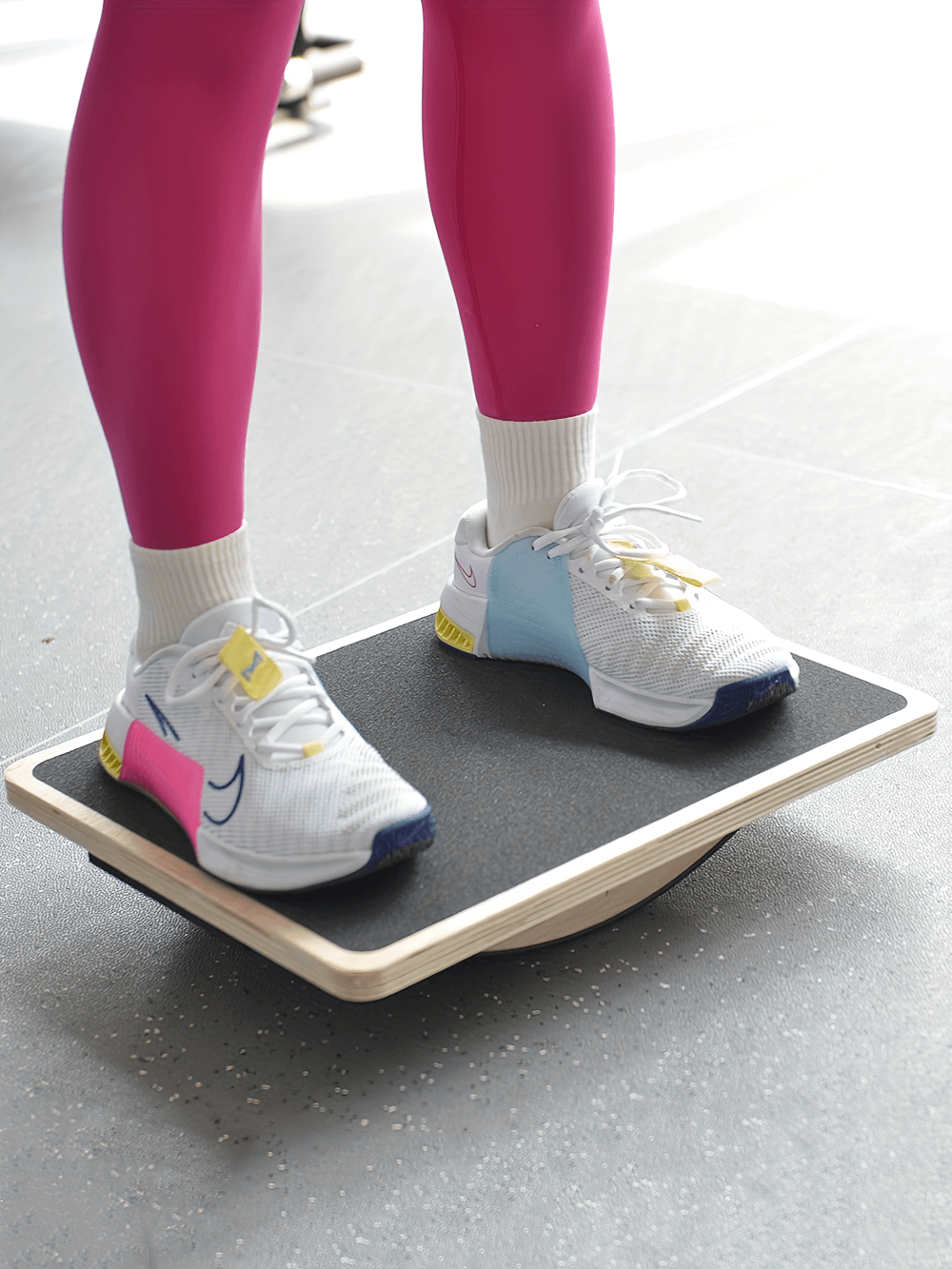 Person using wooden balance board SF2814 for stability training, featuring anti-slip surface and rocker design, wearing colorful sneakers.