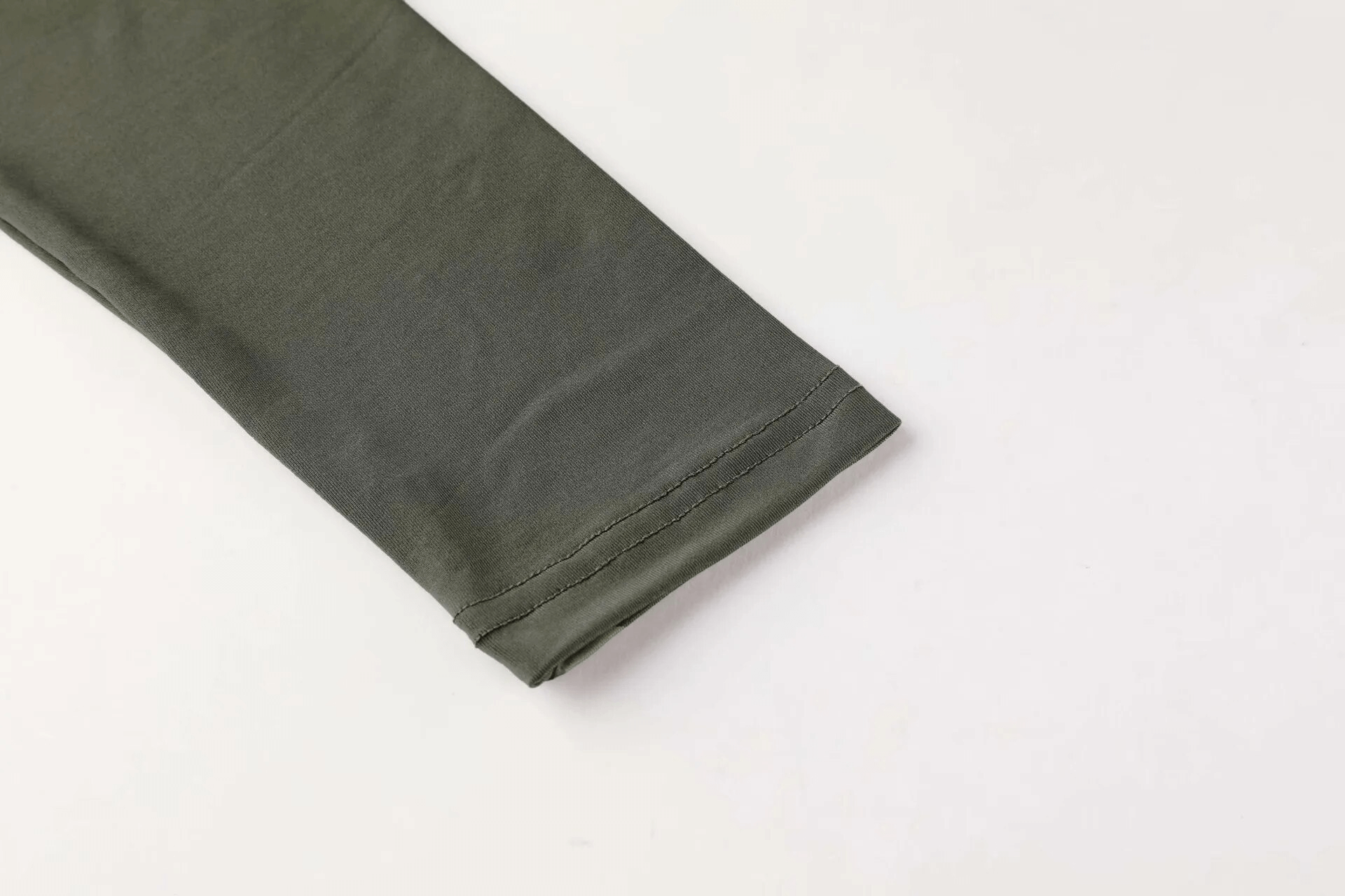 Close-up of green workout long sleeve top fabric, highlighting the smooth texture and quality stitching for men’s activewear.