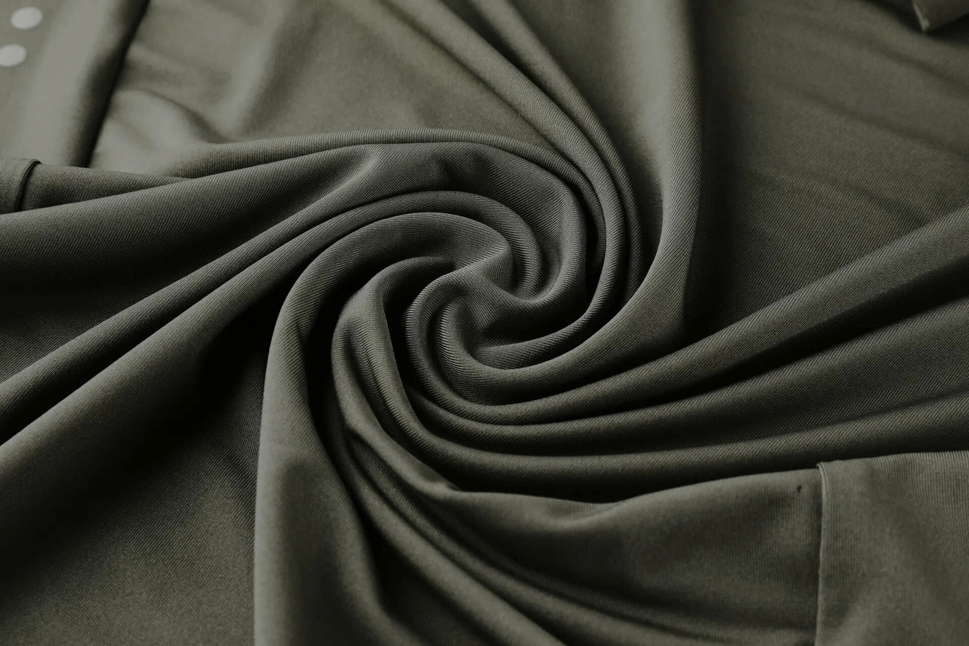 Close-up of dark fabric from men's workout long sleeve top, showcasing swirl pattern and smooth texture.