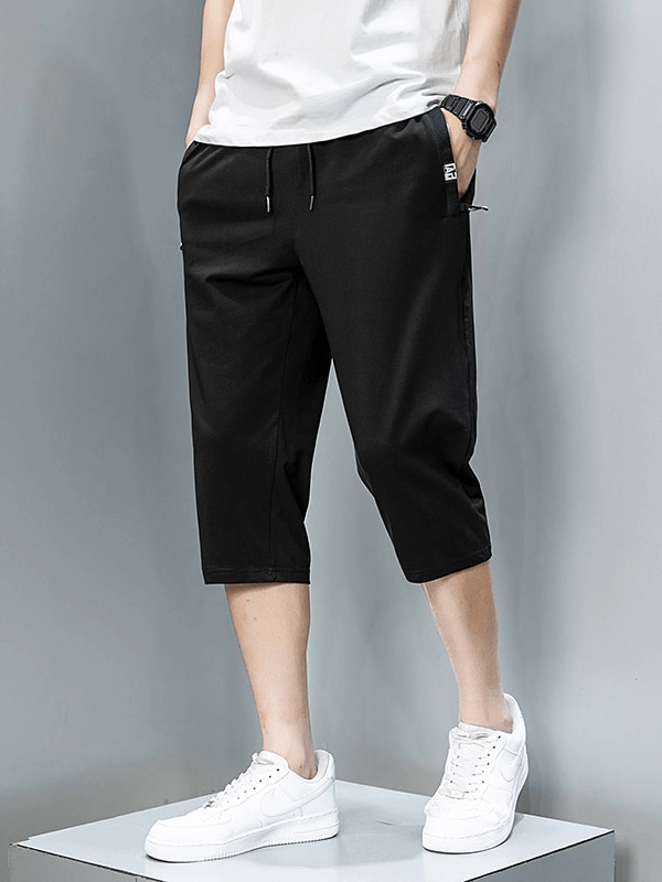 Model wearing black breathable cotton breeches with zip pockets, showcasing casual men's sportswear ideal for outdoor activities.