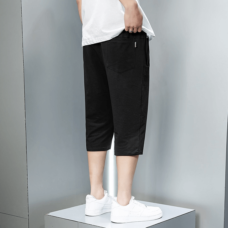 Casual black cotton breeches with zip pockets, mid-waisted design, modeled for men's sportswear fashion.