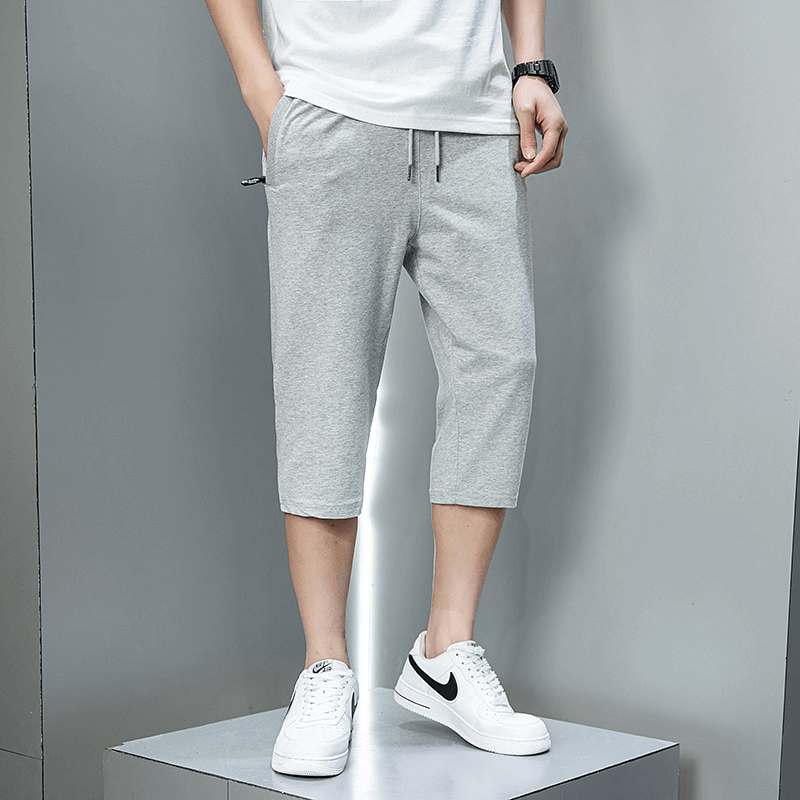 Men wearing gray breathable cotton breeches with zip pockets and drawstring, styled for casual sportswear.