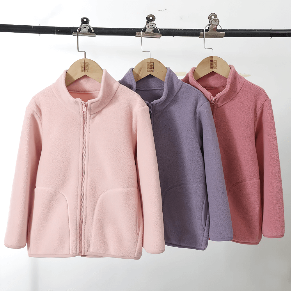 Three pastel Zip-Up Fleece Jackets with Stand Collar - SF3532 hanging on a rack, featuring roomy pockets and cozy design.