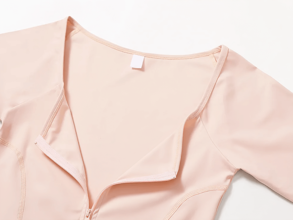 Close-up of a peach zip-up long-sleeved yoga top with front zipper. Ideal for activewear, showcasing chic design and functionality.