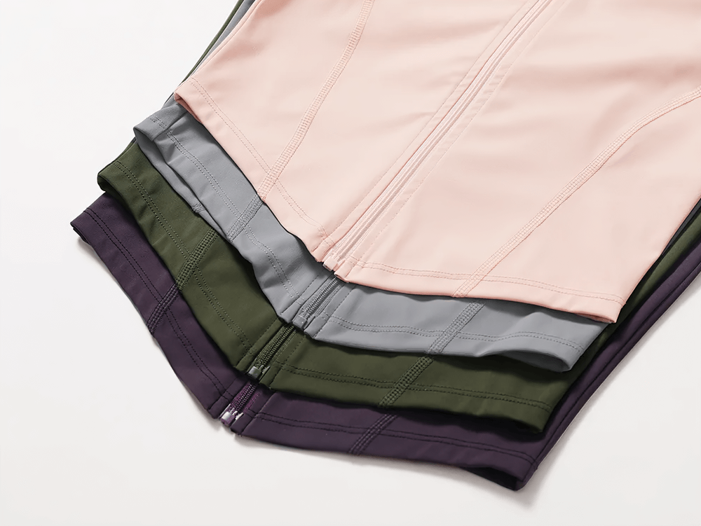 Folded zip-up long-sleeve yoga tops in various colors showcasing zipper and stitching details.