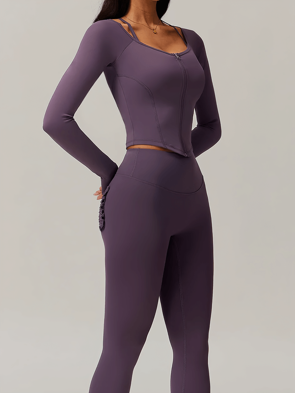 Woman wearing a sleek, purple zip-up long-sleeved yoga top with thumbholes, perfect for workouts and yoga sessions.