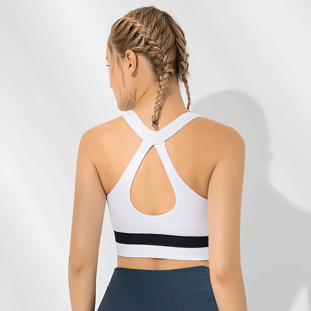 Back view of woman wearing white sports bra with racerback and hollow-out design, showcasing stylish workout attire for fitness activities.