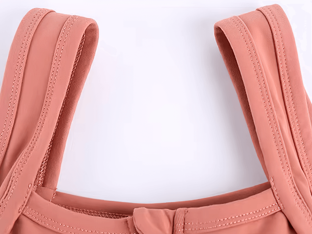 Close-up of pink sports bra with wide adjustable straps and front zipper.