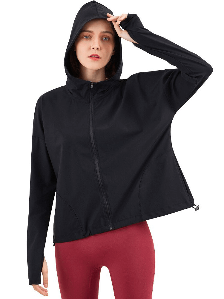 Woman wearing black zipper hood loose fitness jacket with adjustable drawstring and red leggings, perfect for workouts.