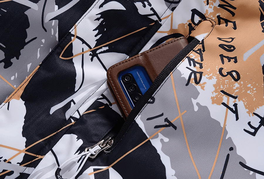 Close-up of waterproof snowboarding jacket with abstract design and zip pocket holding a phone.