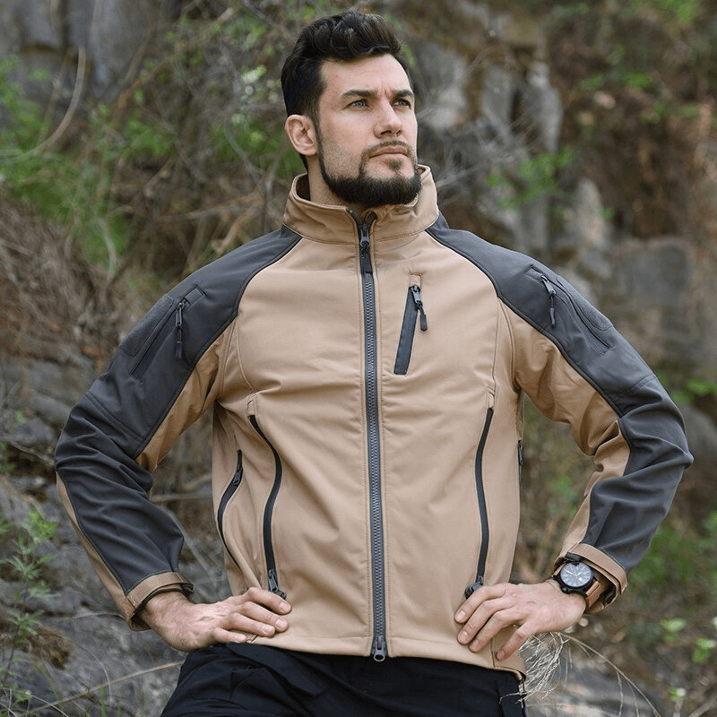 Man wearing brown and gray adjustable cuffs velcro softshell hiking jacket outdoors, showcasing windproof design.
