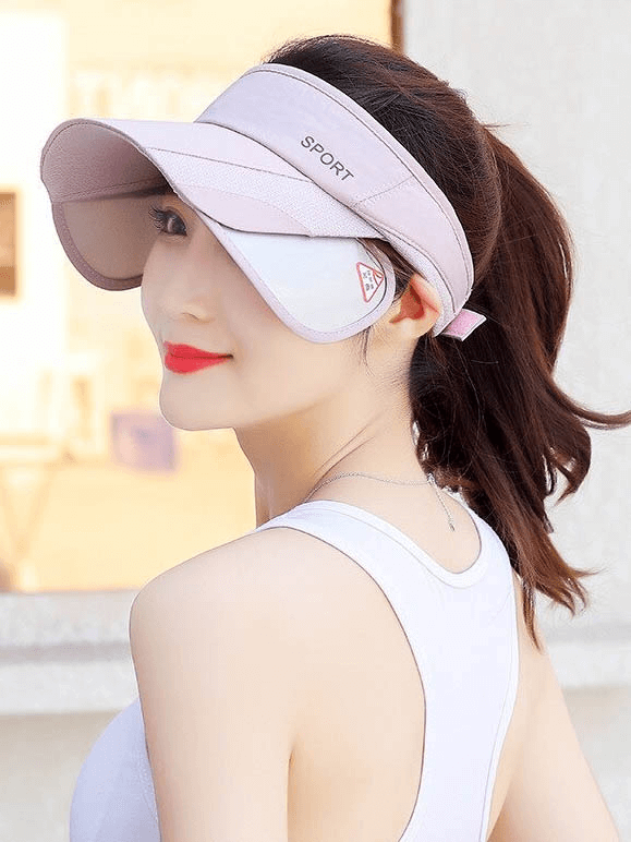 Woman wearing adjustable strap UV protection golf hat, sports sun visor in pink, perfect for outdoor activities and sun protection.