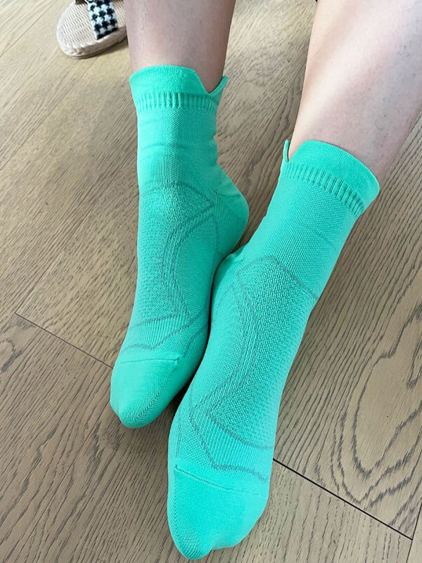 Bright green unisex anti-sweat sport socks for running and fitness on wooden floor, perfect for staying dry and comfortable.