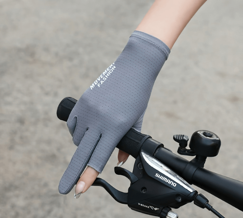 Gray anti-UV cycling glove with open two fingers, providing breathability and grip, worn by a woman while riding a bicycle.