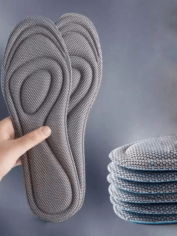 Gray antibacterial massage insoles for sports shoes with memory foam, quick-drying, breathable features held in a hand.