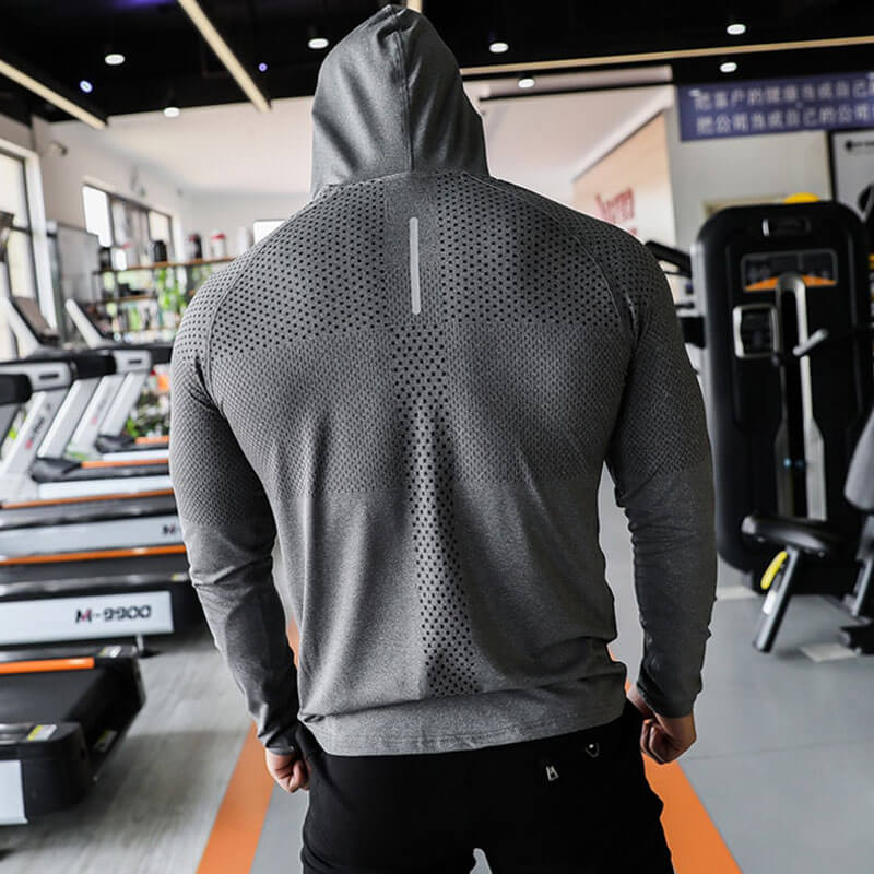 Man wearing athletic men's hooded sweatshirt SF1067 in gym, showcasing workout clothing style designed for comfort and performance.