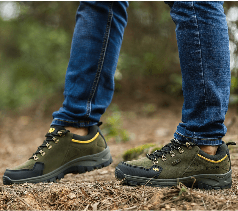 Person wearing green non-slip waterproof hiking shoes with robust rubber outsole on a trail, showcasing outdoor trekking performance.