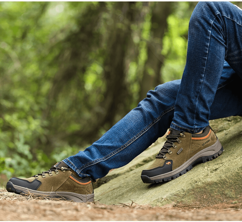 Person wearing athletic non-slip waterproof hiking boots resting on a rock in the forest, showcasing outdoor performance footwear.
