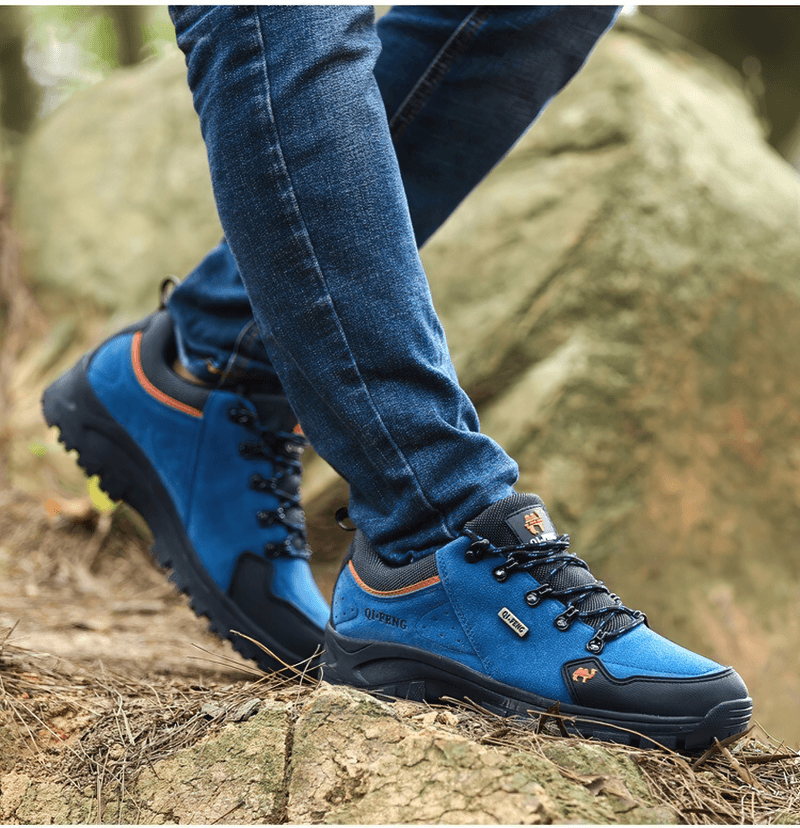 Person wearing blue Athletic Non-slip Waterproof Hiking Shoes SF0246 on rocky terrain for outdoor trekking and hiking.