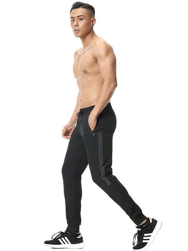 Man modeling athletic soccer running trousers with zip pockets, showcasing comfort and flexibility for sports activities.